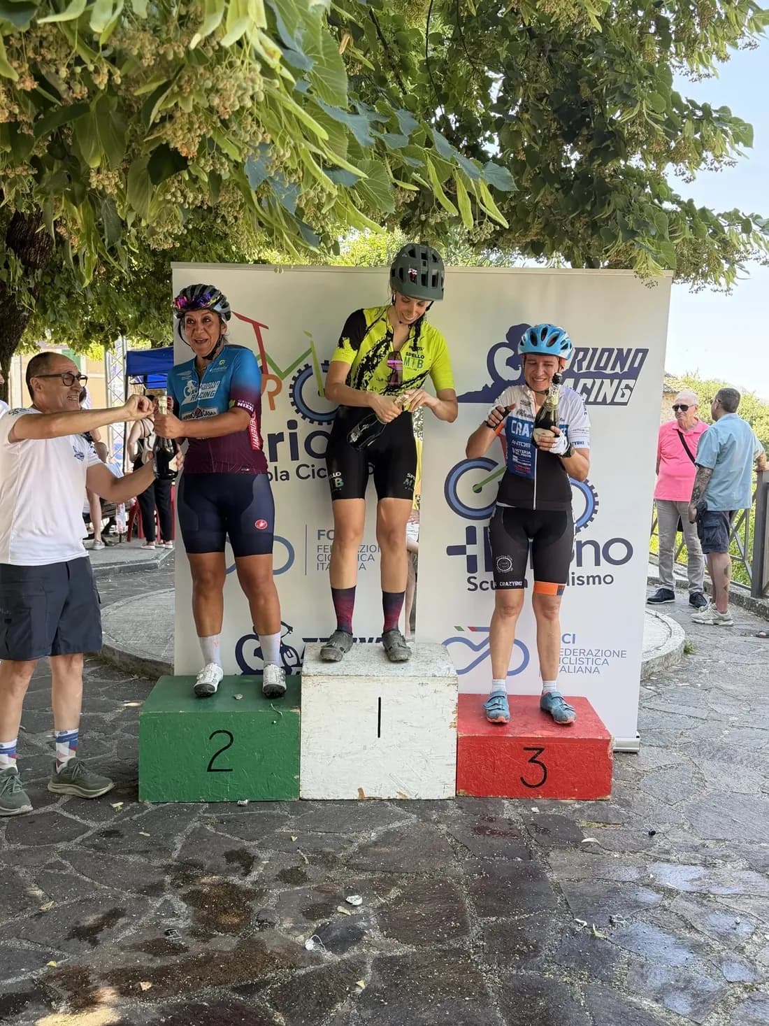 Premiazione della Marathon 209: tre atlete sul podio con il pannello Triono Racing alle spalle