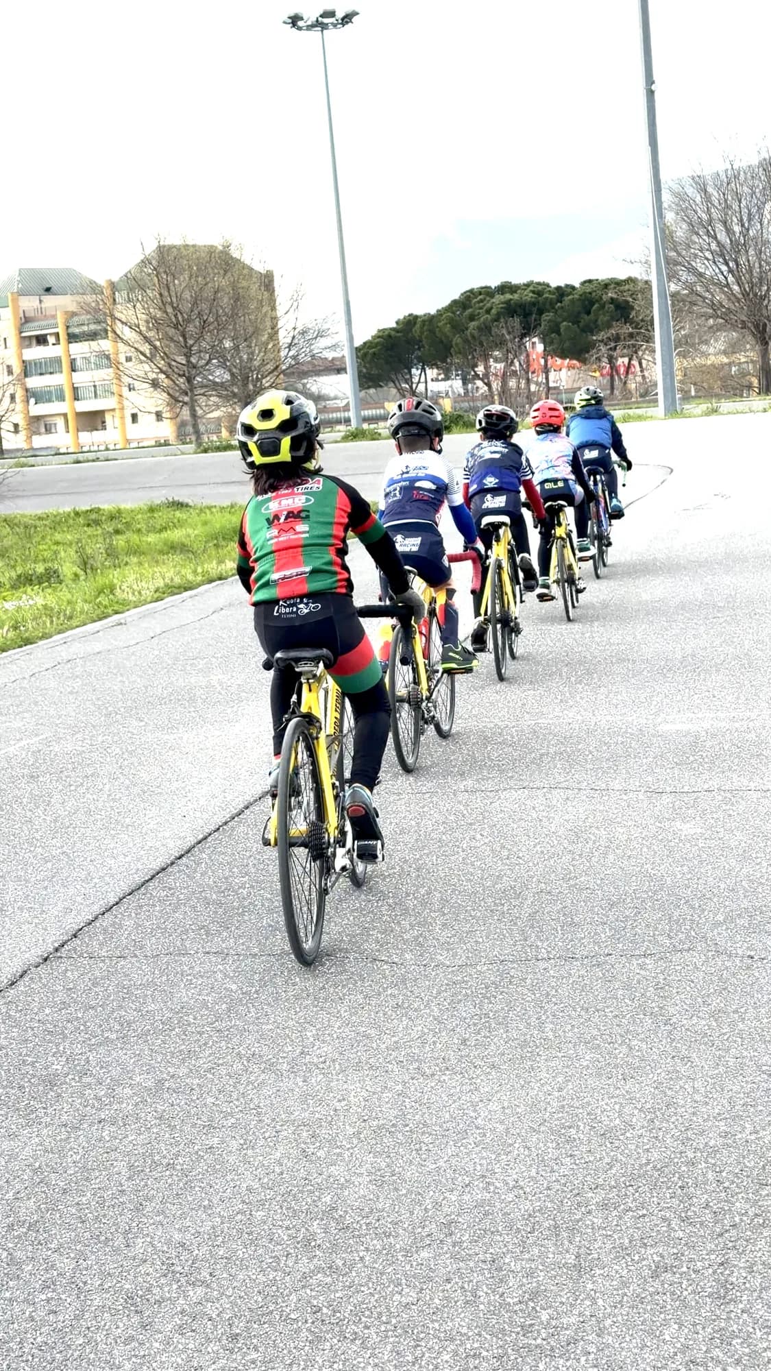Allievi della Scuola Triono in fila indiana sulla pista del ciclodromo, montagne sullo sfondo