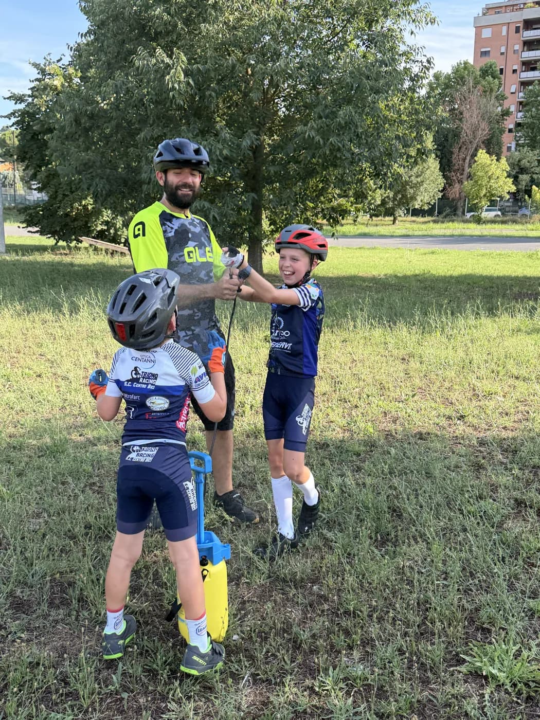 Un maestro della Scuola Triono affianca due giovani allievi in bici, mani sul manubrio, durante una lezione